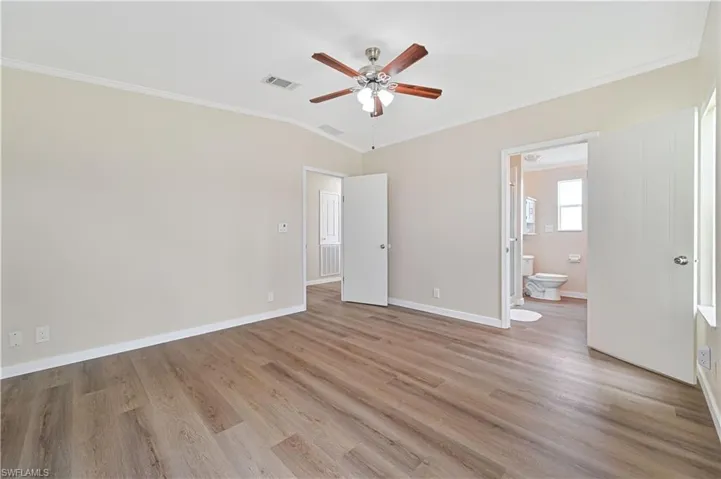Empty room with light wood-type flooring, ceiling fan, crown molding, and vaulted ceiling