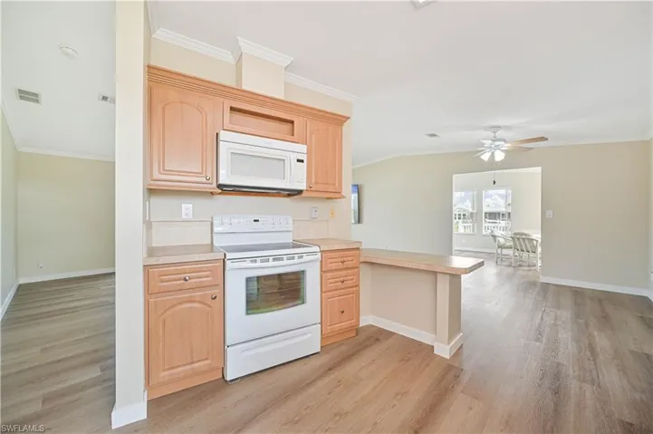Kitchen featuring white appliances, light hardwood / wood-style floors, kitchen peninsula, and ceiling fan