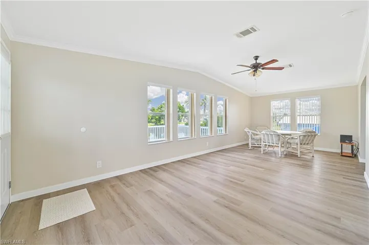 Unfurnished living room featuring light wood-type flooring, vaulted ceiling, crown molding, and ceiling fan