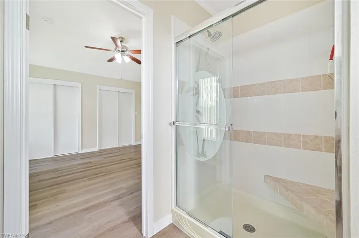 Bathroom with hardwood / wood-style floors, ceiling fan, and a shower with door