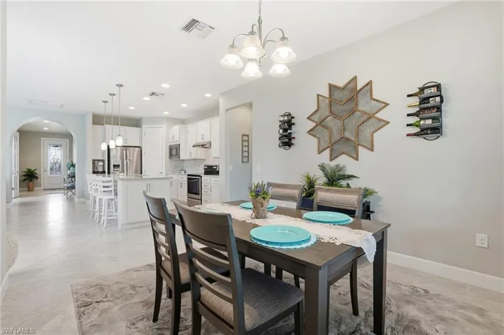 Dining area featuring arched walkways, recessed lighting, a chandelier, and light tile patterned floors