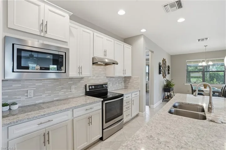 Kitchen with stainless steel range with electric stovetop, recessed lighting, white cabinets, decorative backsplash, and light tile patterned flooring