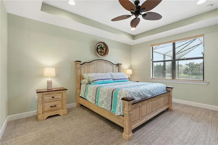 Bedroom featuring light colored carpet, a ceiling fan, a tray ceiling, and recessed lighting