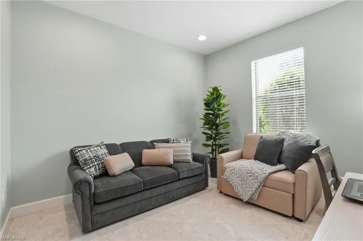 Tiled living room with recessed lighting and baseboards