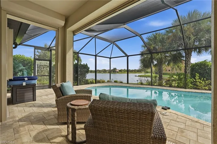Swimming pool featuring a sunroom, a lanai, a water view, and a patio area