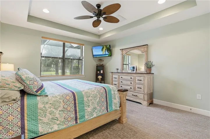 Bedroom with a raised ceiling, light carpet, a ceiling fan, and recessed lighting