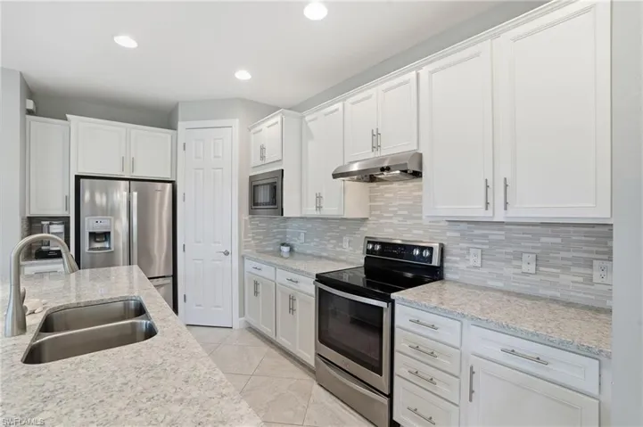 Kitchen featuring stainless steel appliances, tasteful backsplash, white cabinets, and recessed lighting