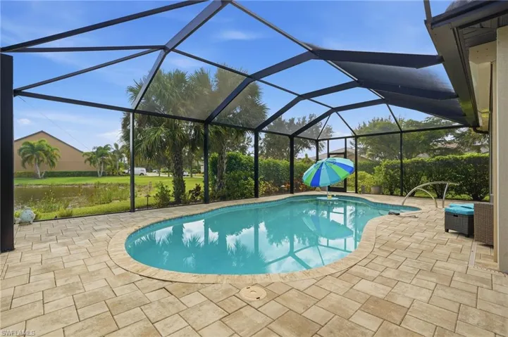 Outdoor pool with glass enclosure, a sunroom, and a patio
