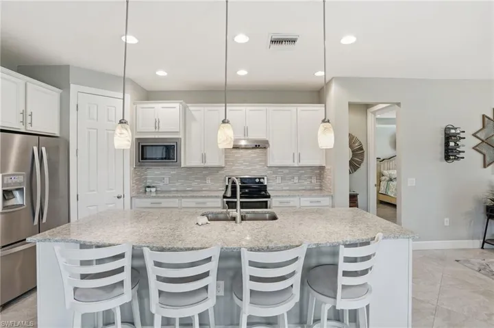 Kitchen featuring appliances with stainless steel finishes, white cabinets, tasteful backsplash, decorative light fixtures, and recessed lighting