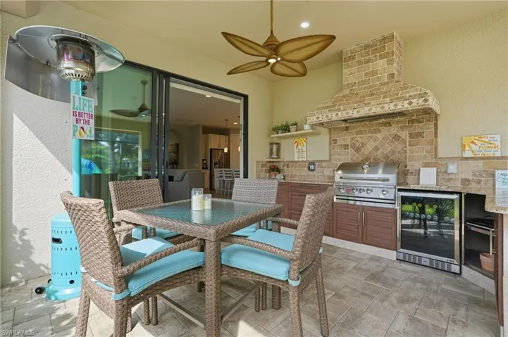 View of patio / terrace featuring exterior kitchen, ceiling fan, outdoor dining area, and beverage cooler