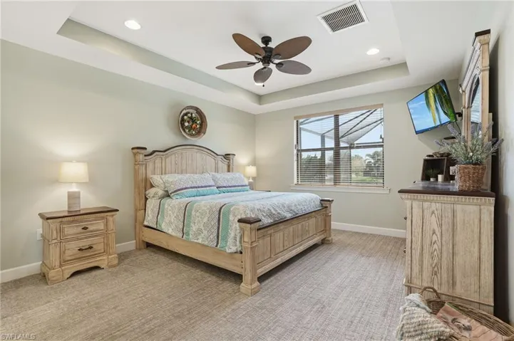 Bedroom featuring a raised ceiling, light carpet, a ceiling fan, and recessed lighting
