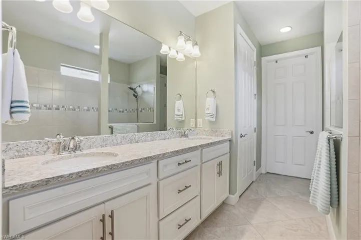 Bathroom with walk in shower, double vanity, and light tile patterned floors