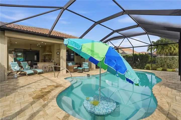 Swimming pool featuring glass enclosure, a sunroom, a patio area, and an outdoor hangout area