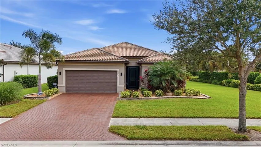 View of front of home with stucco siding, decorative driveway, a tiled roof, an attached garage, and a front lawn