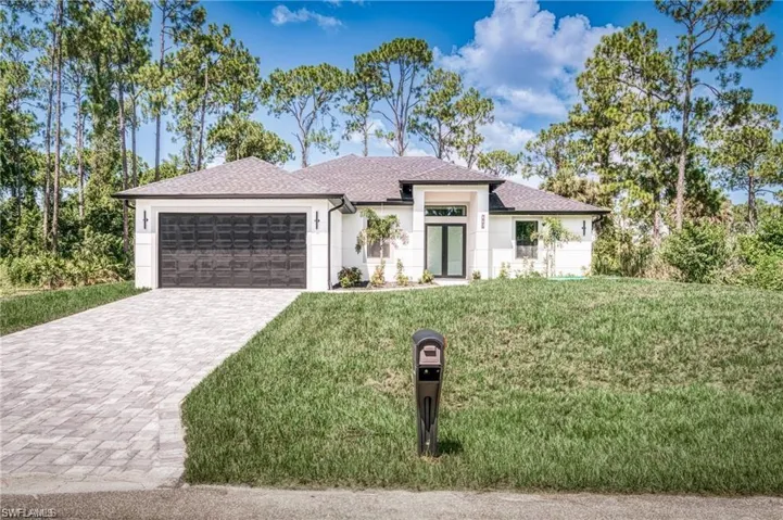 Prairie-style home featuring an attached garage, decorative driveway, a front yard, and stucco siding
