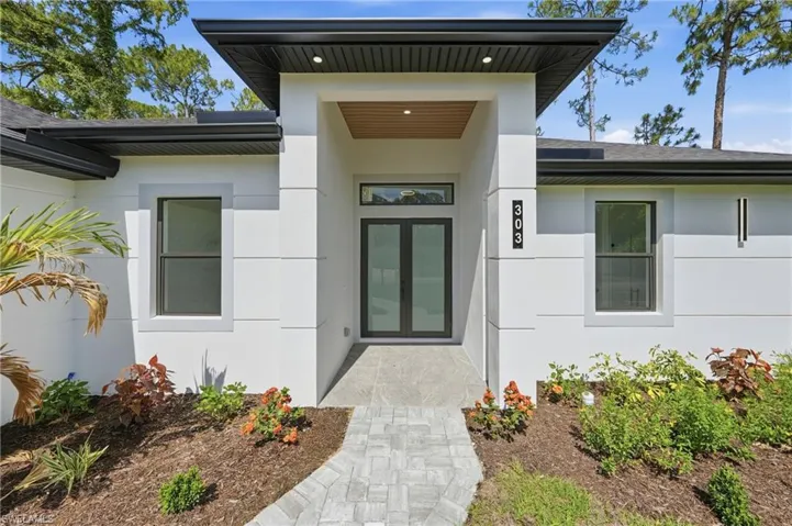 Contemporary home entrance featuring a covered porch, wood-finish ceiling accent, and double-pane glass entry doors