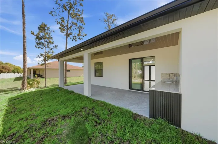 Covered patio with integrated outdoor kitchen featuring a sink and countertop