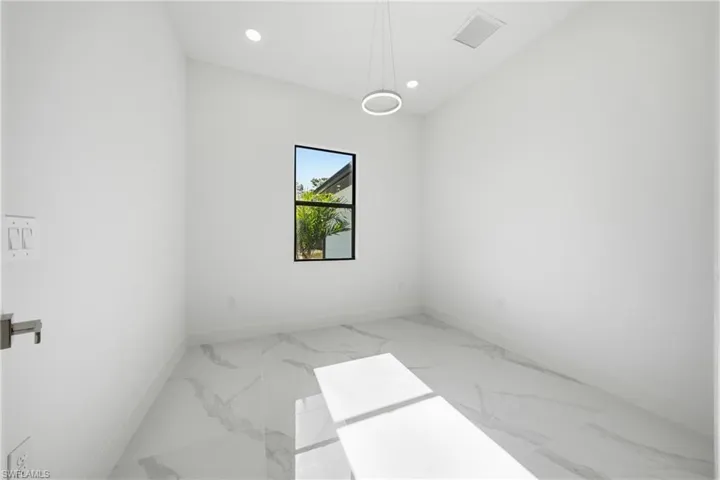 Bright room featuring white walls, large format tile flooring with a subtle veining pattern, and a black-framed window