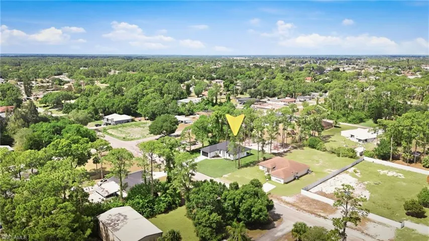 Aerial perspective showcasing a residential property with a detached garage, surrounded by mature trees and lush greenery