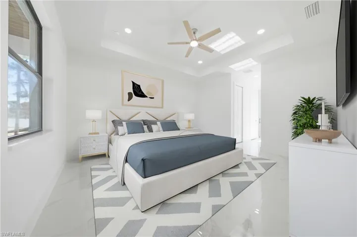 Bedroom featuring a tray ceiling with recessed lighting and a ceiling fan