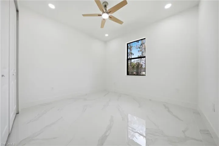 Spacious room featuring large format tile flooring, recessed lighting, and a modern ceiling fan