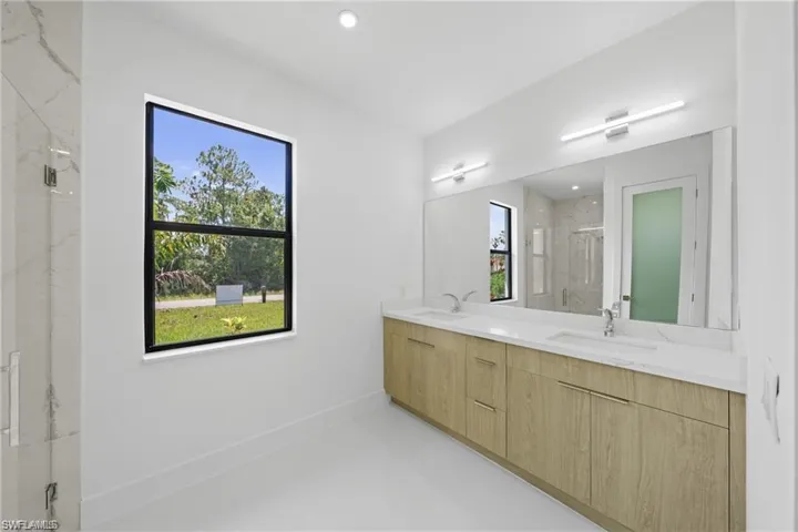Bathroom with double vanity, a marble finish shower, finished concrete floors, and recessed lighting