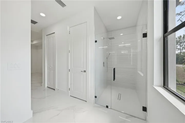 Contemporary shower with clear glass enclosure and black hardware, featuring a rainfall showerhead and linear floor drain