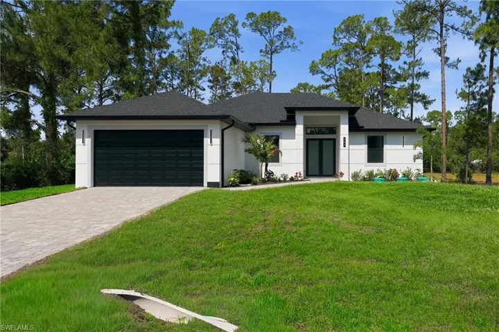 Prairie-style home featuring an attached garage, decorative driveway, a front yard, and stucco siding