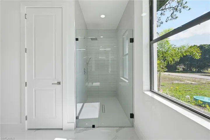 Contemporary bathroom featuring a spacious glass-enclosed shower with a linear drain, white subway tile surround, and a rain shower head
