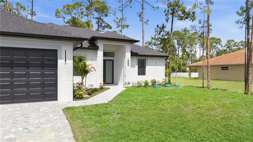 Modern single-story residence featuring a dark asphalt shingle roof, white stucco exterior, and a dark paneled garage door