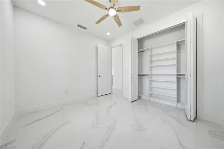 Room featuring wood-finish ceiling fan, recessed lighting, and a closet with custom shelving and bifold doors