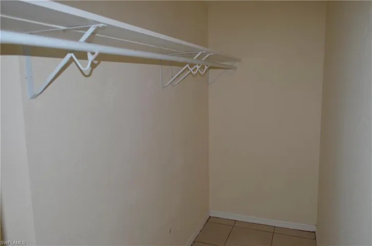 Spacious primary closet with light tile patterned floors