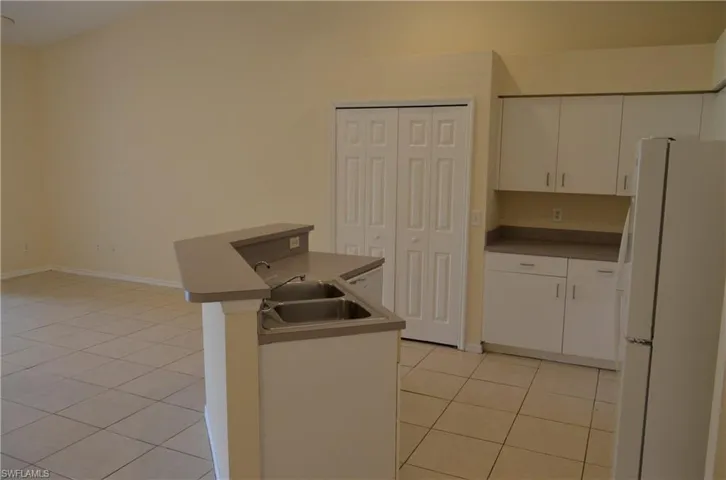Kitchen with white appliances, light tile patterned floors, and white cabinets