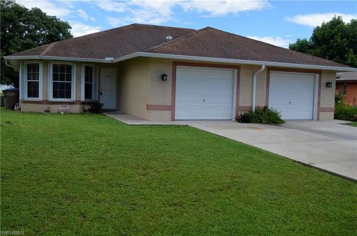 Ranch-style duplex featuring a shingled roof, a front yard, stucco siding, driveway, and an attached garage