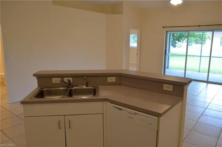 Kitchen featuring light tile patterned floors, white cabinets, white dishwasher, open floor plan, and a ceiling fan