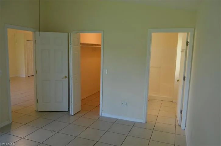Unfurnished bedroom with light tile patterned floors and a walk in closet