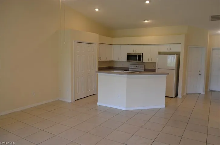 Kitchen with white appliances, white cabinetry, light tile patterned floors, recessed lighting, and a center island