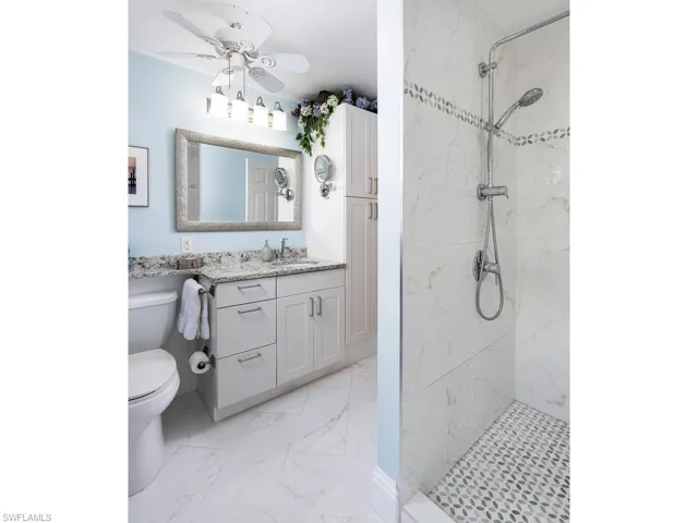 Full bath floor in marble patterned tile, walls of shower are tile, trim in shower is marble, marble floor in shower