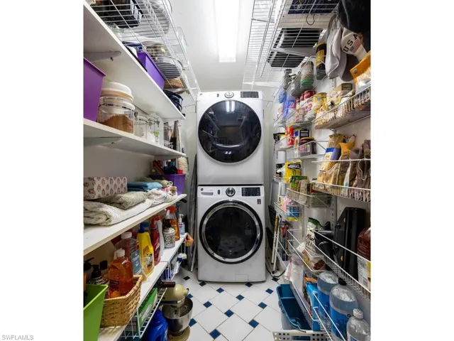 Laundry/pantry area with tile patterned floors, stacked washer and clothes dryer