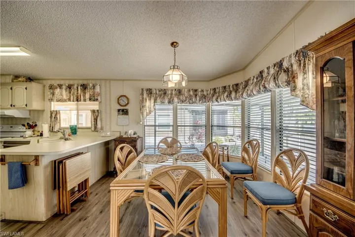 Dining room with a textured ceiling, light wood-style flooring, and vaulted ceiling