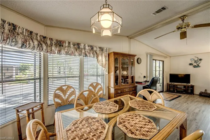 Dining area with a textured ceiling, ceiling fan, light wood-style flooring, and an office area