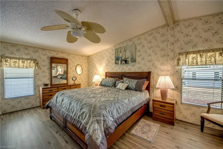 Bedroom with light wood-style floors, a ceiling fan, a textured ceiling, and wallpapered walls