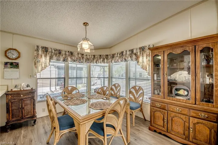 Dining space featuring lofted ceiling, a textured ceiling, light wood-type flooring, and a decorative wall