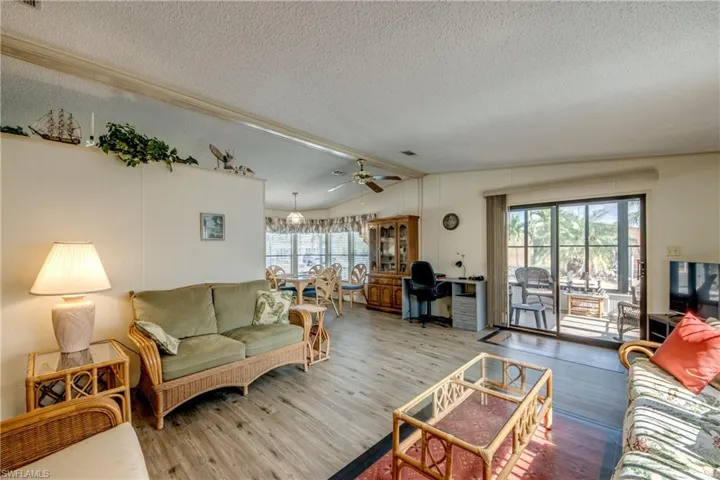 Living area with wood finished floors, a textured ceiling, lofted ceiling, and a ceiling fan