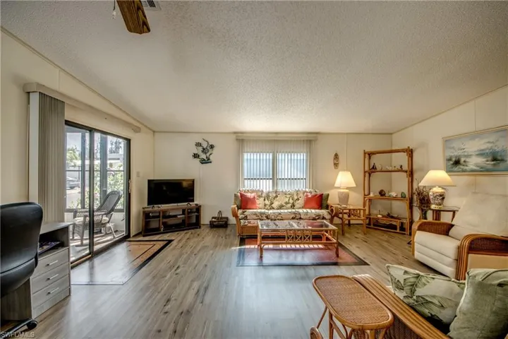 Living room with a textured ceiling, wood finished floors, and vaulted ceiling