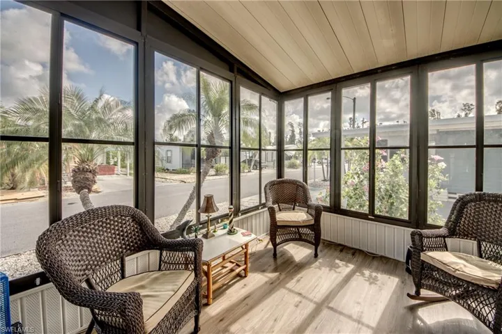 Sunroom / solarium with wood finished floors, healthy amount of natural light, and lofted ceiling