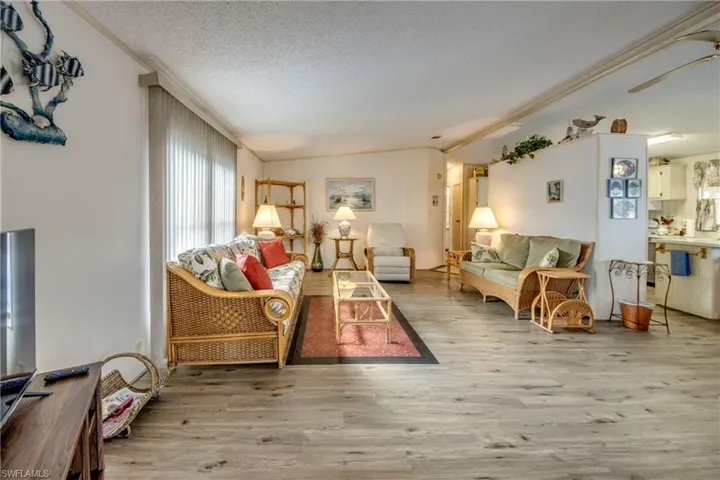 Living area featuring light wood finished floors, a textured ceiling, lofted ceiling, and a ceiling fan