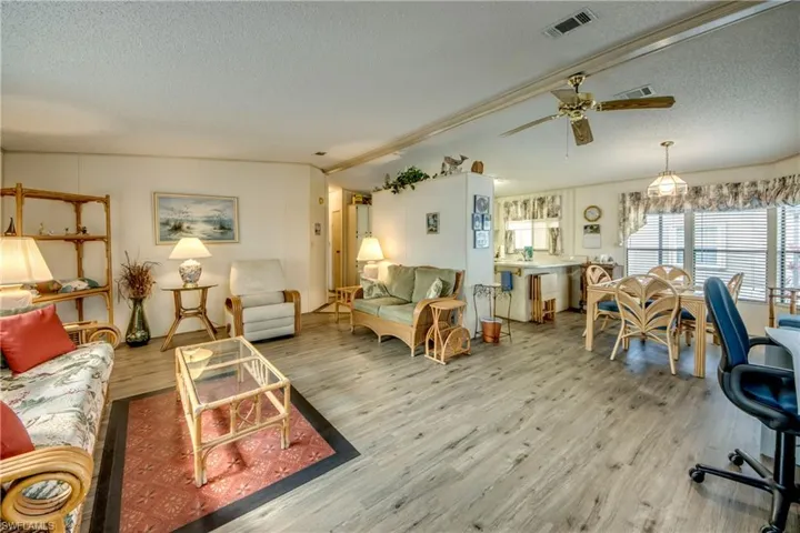 Living area featuring a textured ceiling, wood finished floors, and ceiling fan