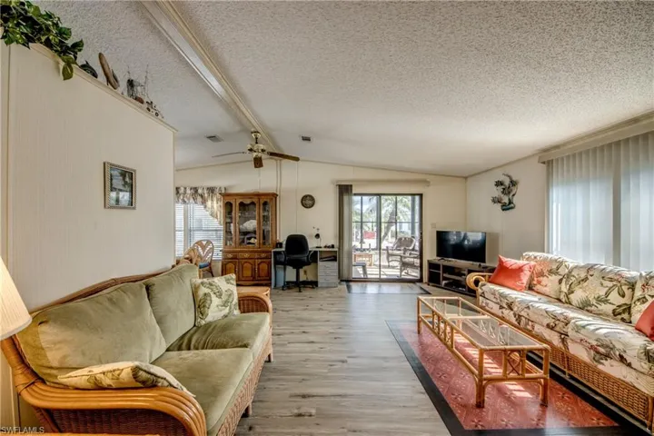 Living area with plenty of natural light, light wood finished floors, a textured ceiling, a ceiling fan, and an office area