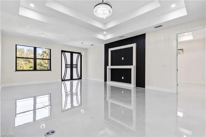 Spare room featuring a raised ceiling and suspended lighting
